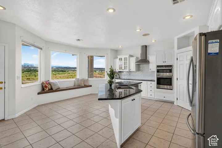 Modern kitchen featuring white cabinetry, stainless steel appliances, a center island with dark countertops, and tile flooring