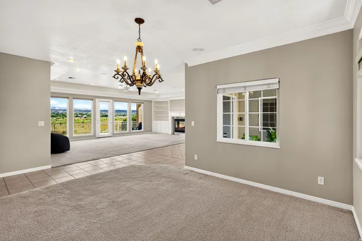 Expansive room featuring a decorative chandelier, large windows, and a built-in fireplace