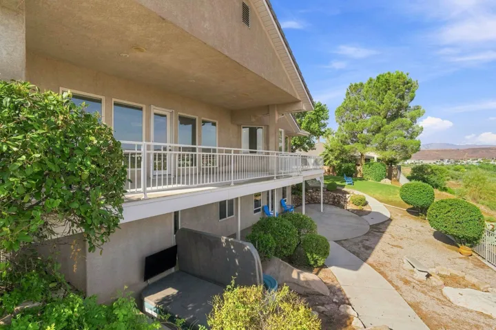 Multi-level residence with a stucco exterior, upper-level balcony, and ground-level patio