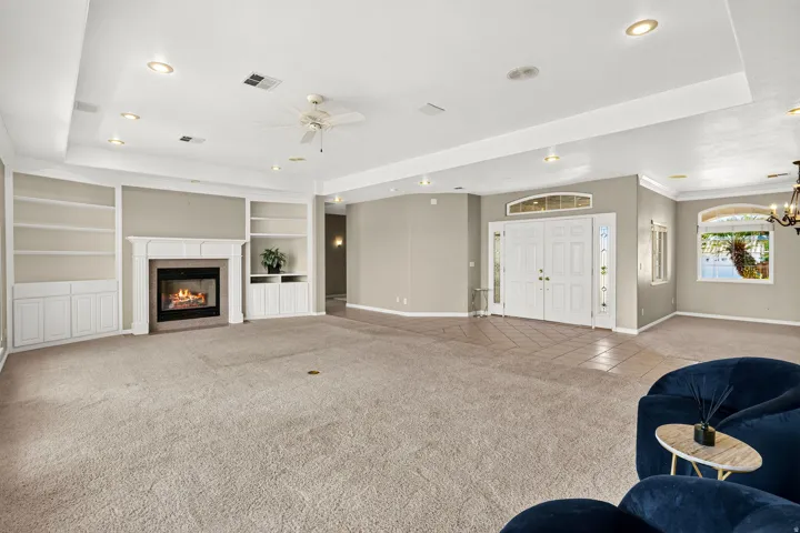 Built-in shelving and cabinetry framing a fireplace, recessed lighting, double entry doors with an arched transom, and arched windows