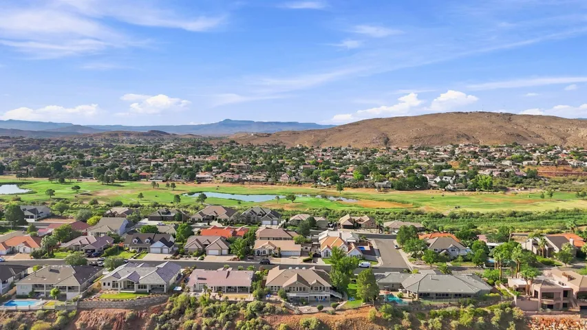 Aerial perspective showcasing a residential community with mature landscaping, a golf course, and natural terrain