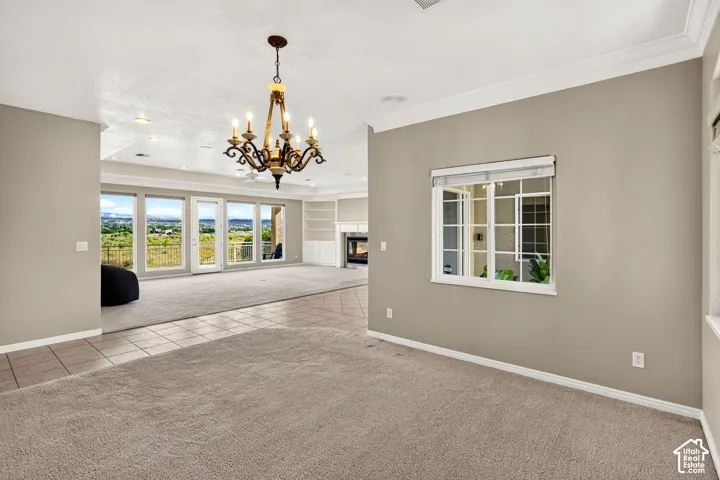 Expansive room featuring a decorative chandelier, large windows, and a built-in fireplace
