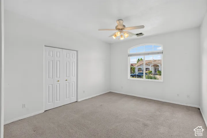 Neutral wall paint, carpet flooring, a bifold closet, and an arched window