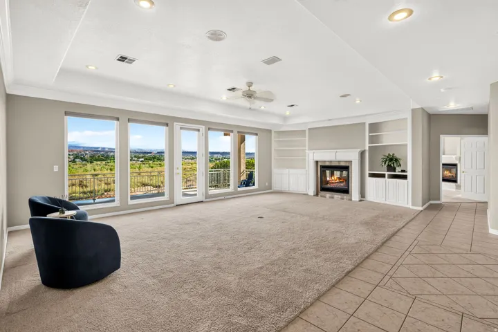 Spacious interior featuring a built-in fireplace, custom shelving, recessed lighting, and expansive windows