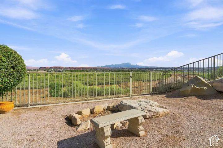 Gravel patio featuring a stone bench, fire pit area with natural rock surround, and metal fencing