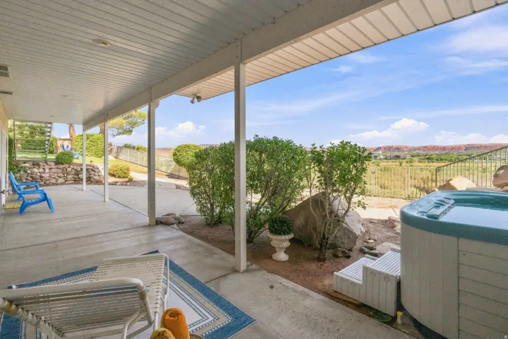 Spacious covered patio with concrete flooring, integrated hot tub, and open-air fencing