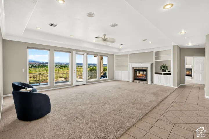 Spacious interior featuring a built-in fireplace, custom shelving, recessed lighting, and expansive windows