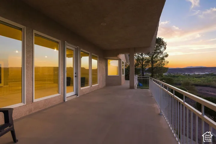 Expansive balcony with a smooth concrete surface, multiple large windows, and a white metal railing