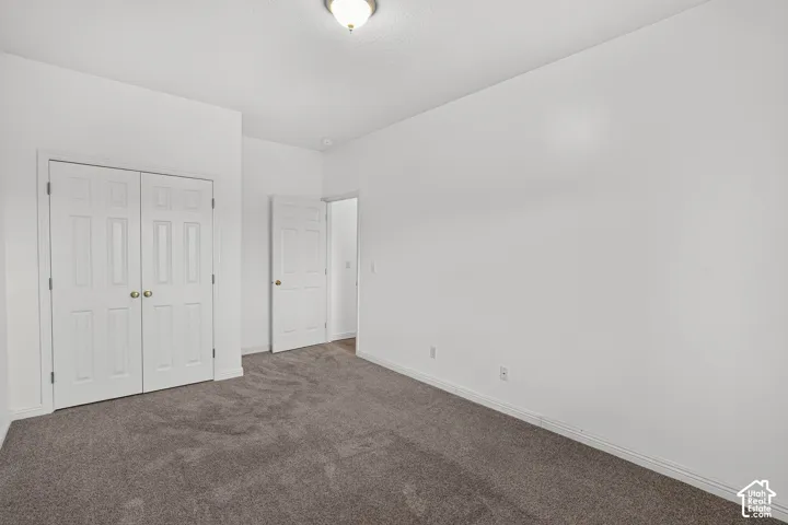 Spacious bedroom with neutral wall finishes, plush carpeting, and dual closets featuring white six-panel doors