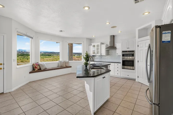 Modern kitchen featuring white cabinetry, stainless steel appliances, a center island with dark countertops, and tile flooring