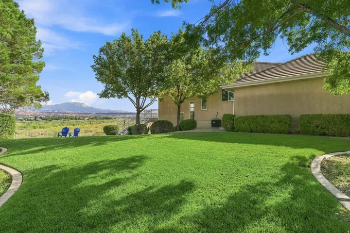 Expansive lawn with concrete curbing, mature trees, and stucco exterior