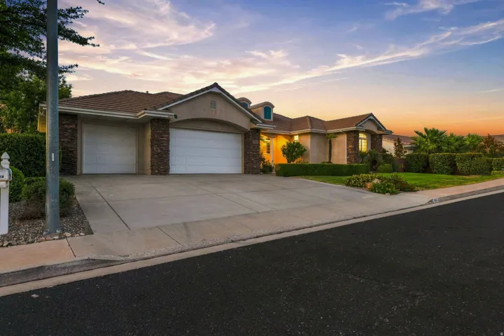 Stucco exterior with stone accents, a tile roof, two garage doors, and a concrete driveway