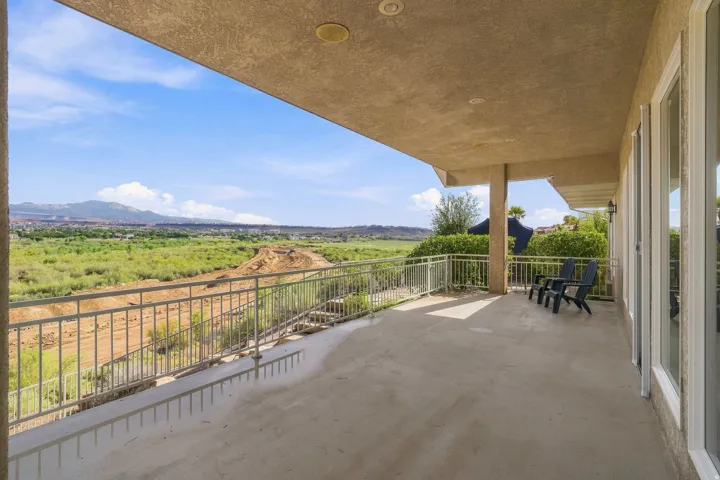 Expansive covered patio with concrete flooring, recessed lighting, and a metal railing
