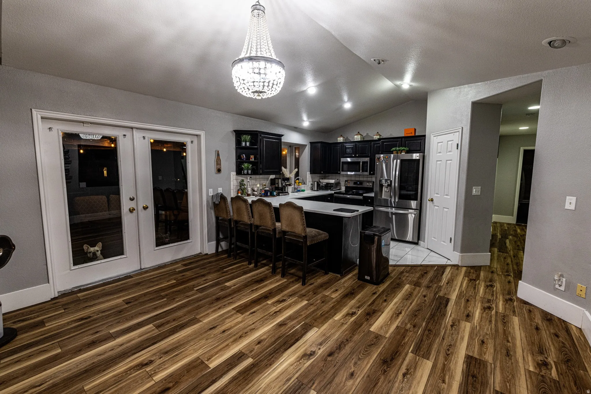 Spacious kitchen featuring dark cabinetry, stainless steel appliances, a center island with seating, and wood-finish flooring