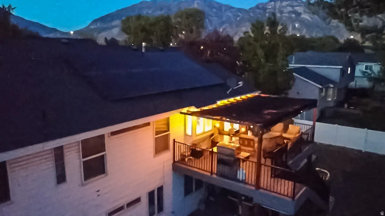 Multi-level exterior deck featuring metal railings, a covered patio area with string lights, and a lower-level concrete patio