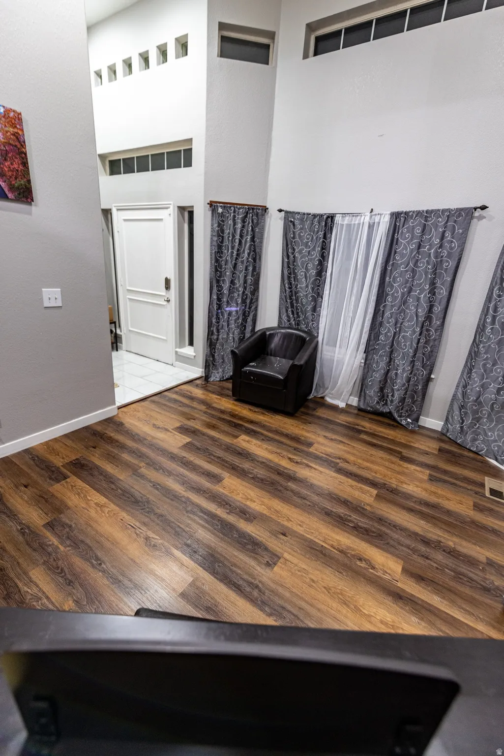 Wood-finish flooring throughout, a white entry door with frosted glass sidelight, and multiple transom windows