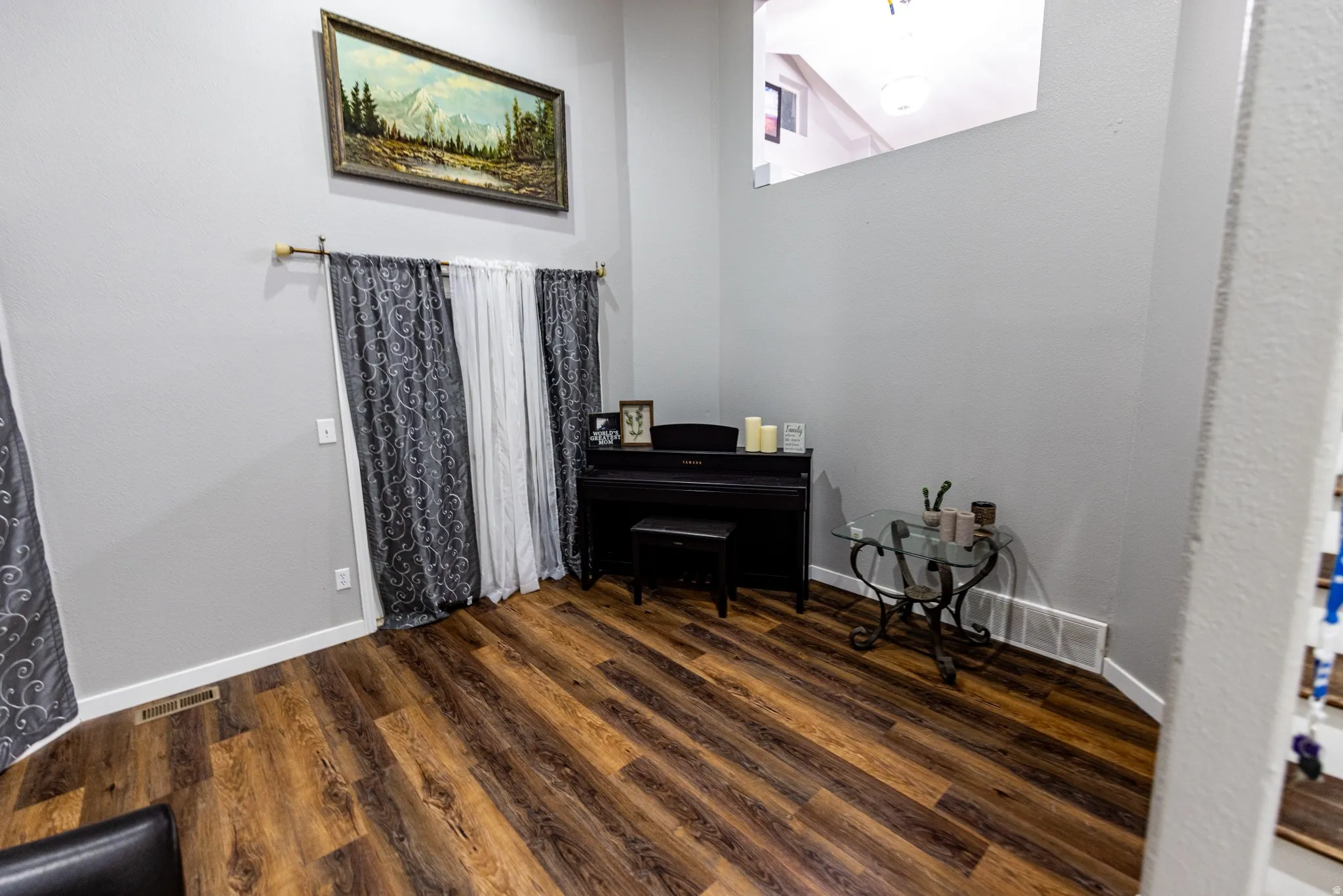 Wood-finish flooring with light gray walls, white trim, and a high ceiling