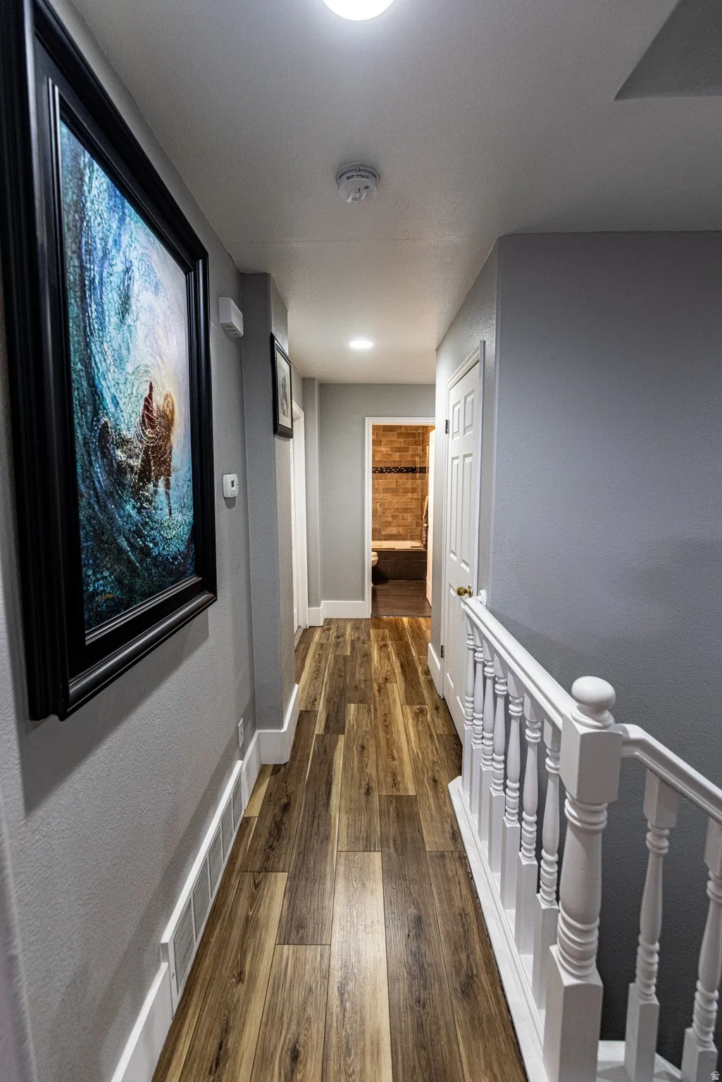 Wood-finish flooring, recessed lighting, and a white baluster railing