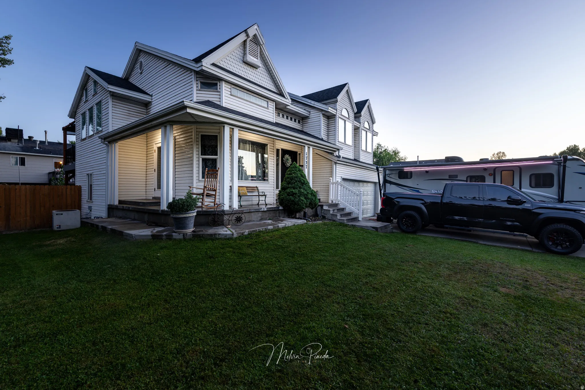 Gable roofline, covered front porch, white siding, attached garage, and mature landscaping