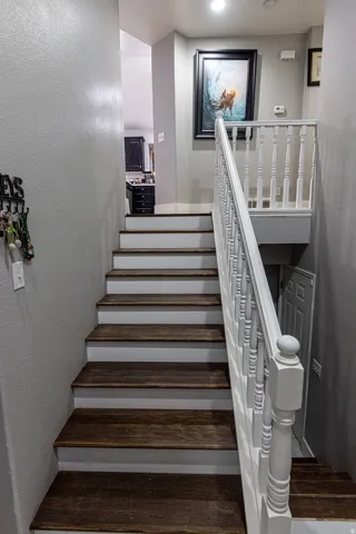 Staircase featuring wood-finish treads, white risers, and a white baluster railing