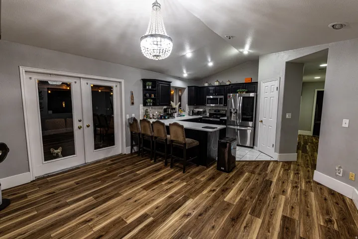 Spacious kitchen featuring dark cabinetry, stainless steel appliances, a center island with seating, and wood-finish flooring