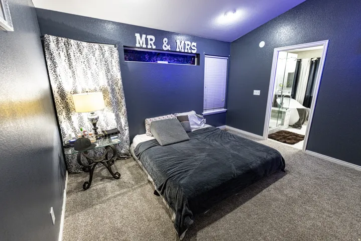 Carpeted room with a window featuring blinds, an entryway, and a permanent wall-mounted decorative element
