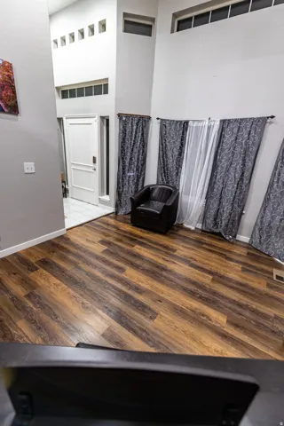 Wood-finish flooring throughout, a white entry door with frosted glass sidelight, and multiple transom windows
