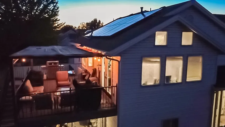 Upper-level deck with a fabric-covered pergola and metal railings