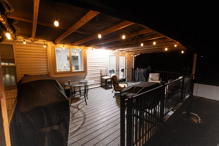 Expansive covered deck featuring composite decking, string lighting, and direct access to interior spaces