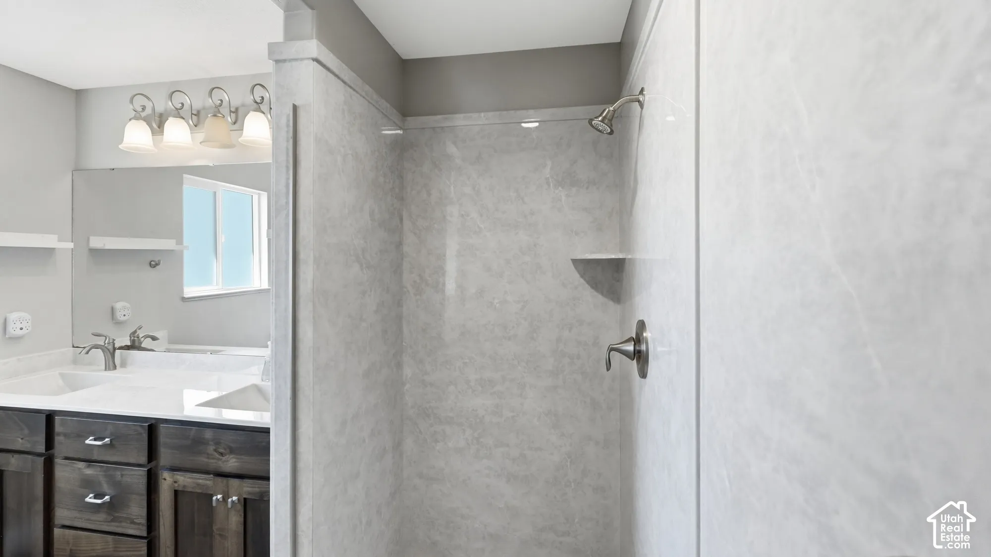 Walk-in shower with light-toned wall panels, built-in shelving, and a brushed nickel shower head