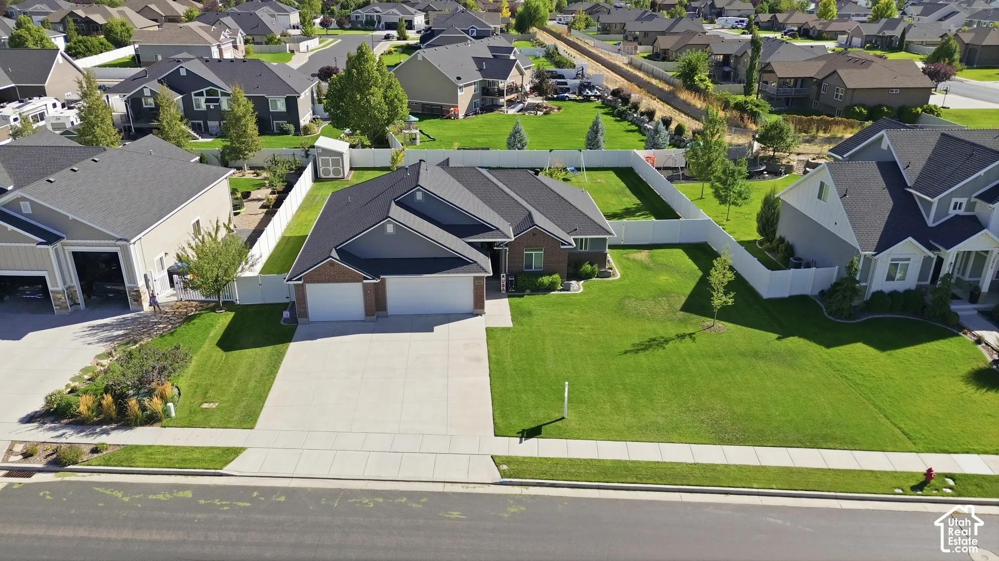 Siding exterior with brick accents, attached two-car garage, concrete driveway, fenced backyard, and mature landscaping