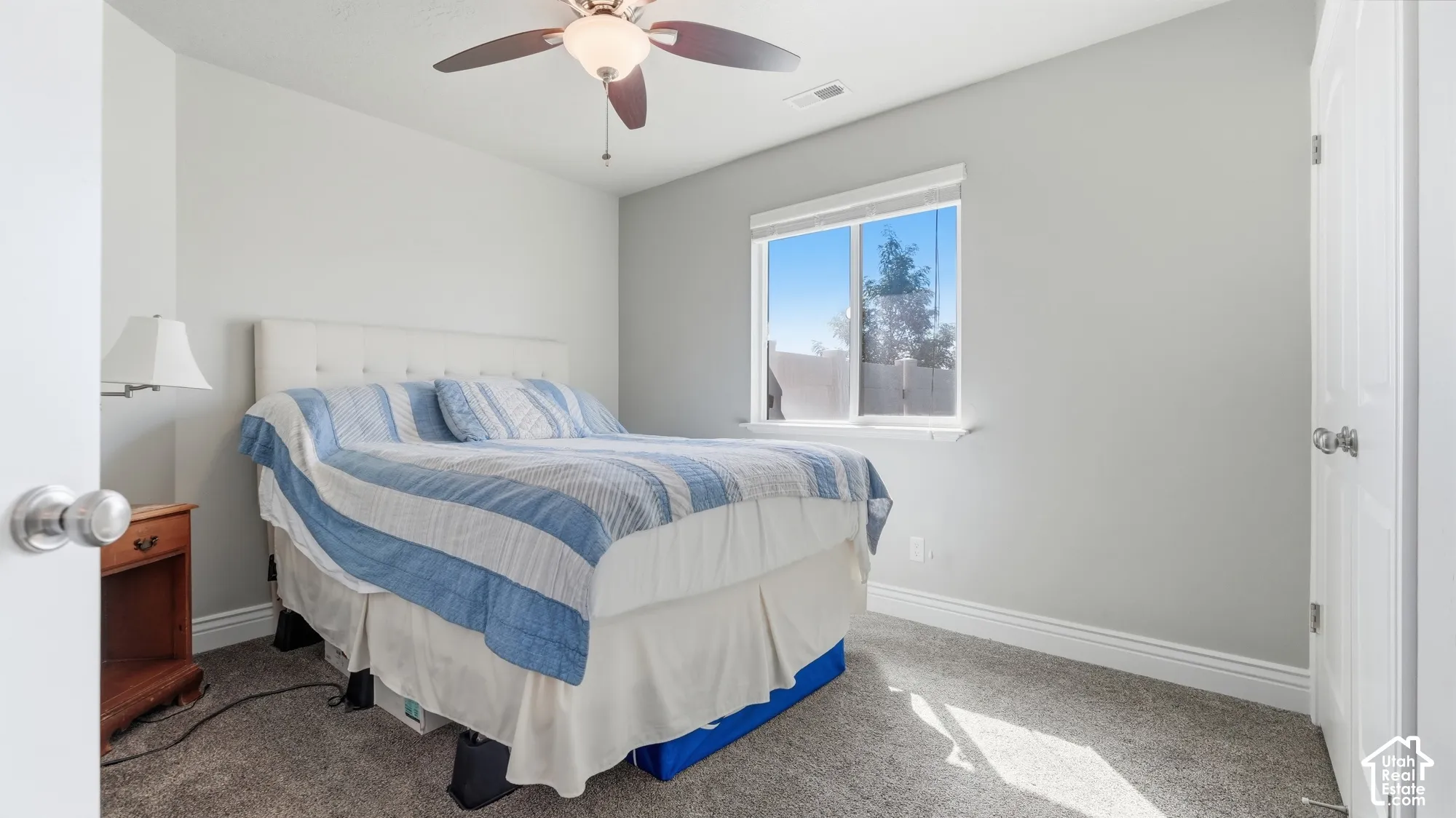 Neutral wall paint, carpet flooring, a ceiling fan with integrated lighting, and a white-framed window