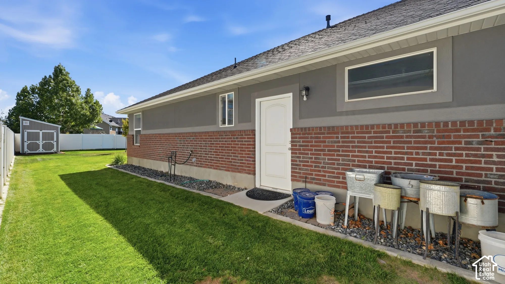 Brick and stucco exterior with multiple windows and a white entry door