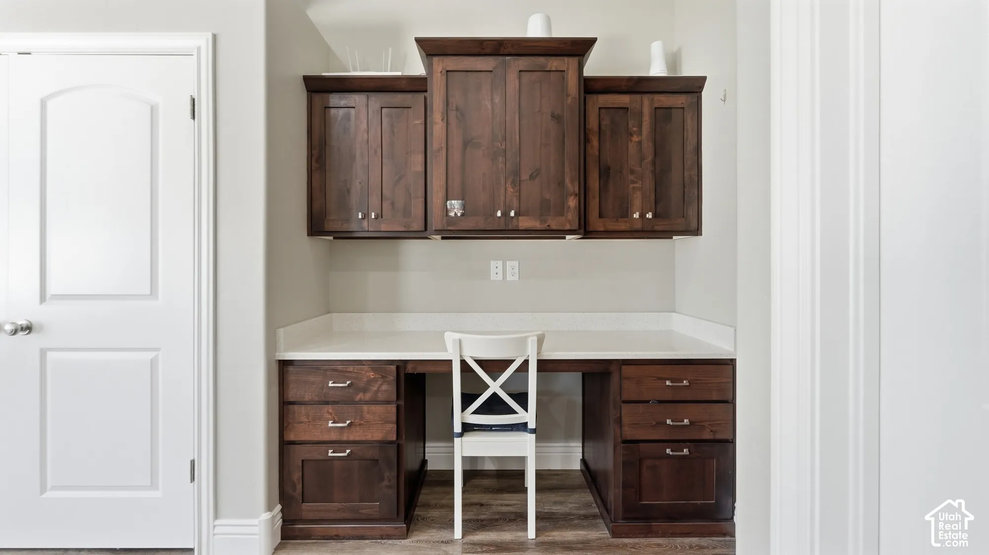 Built-in desk featuring dark wood-finish cabinetry, a light-toned countertop, and recessed lighting