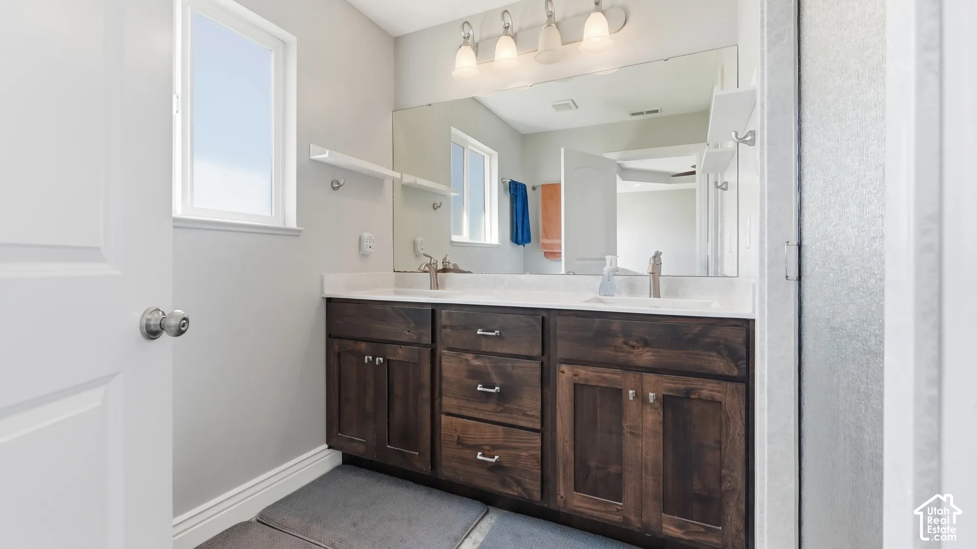 Dual sink vanity with dark wood-finish cabinetry, white countertops, and brushed nickel faucets