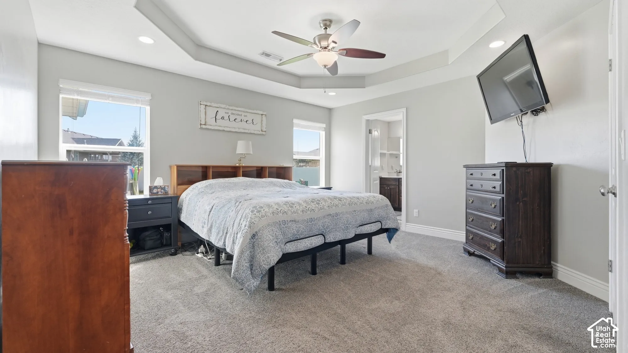 Tray ceiling with a ceiling fan, dual windows, and recessed lighting