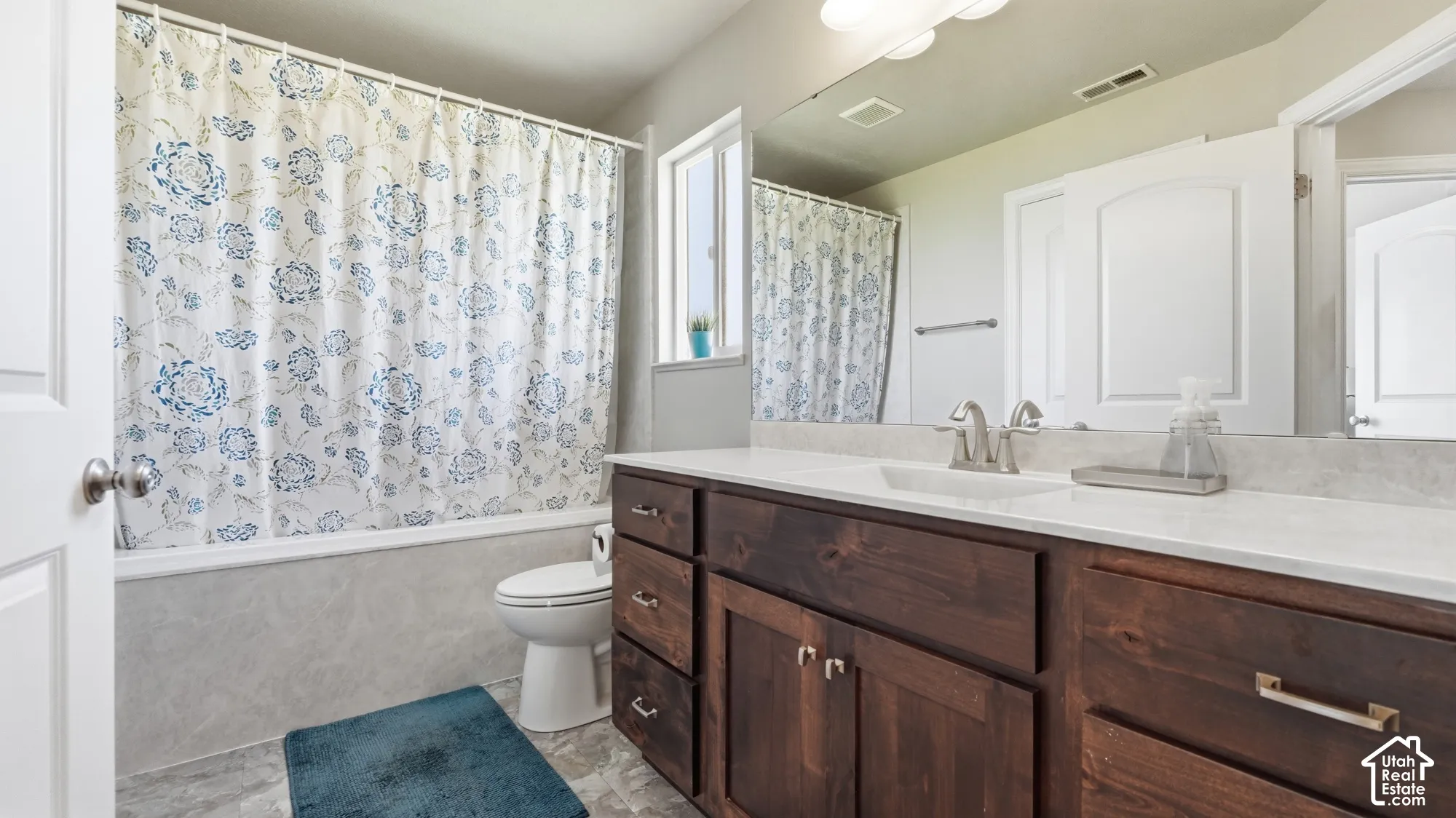 Wood-finish vanity with an integrated sink, polished chrome faucet, and spacious mirror