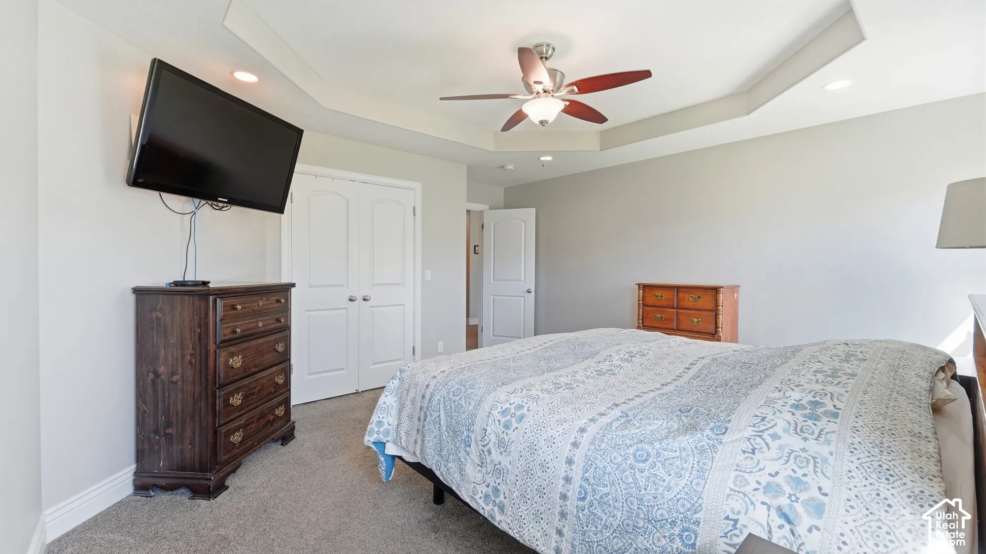 Tray ceiling with recessed lighting, ceiling fan with light fixture, light gray wall finish, and white paneled doors