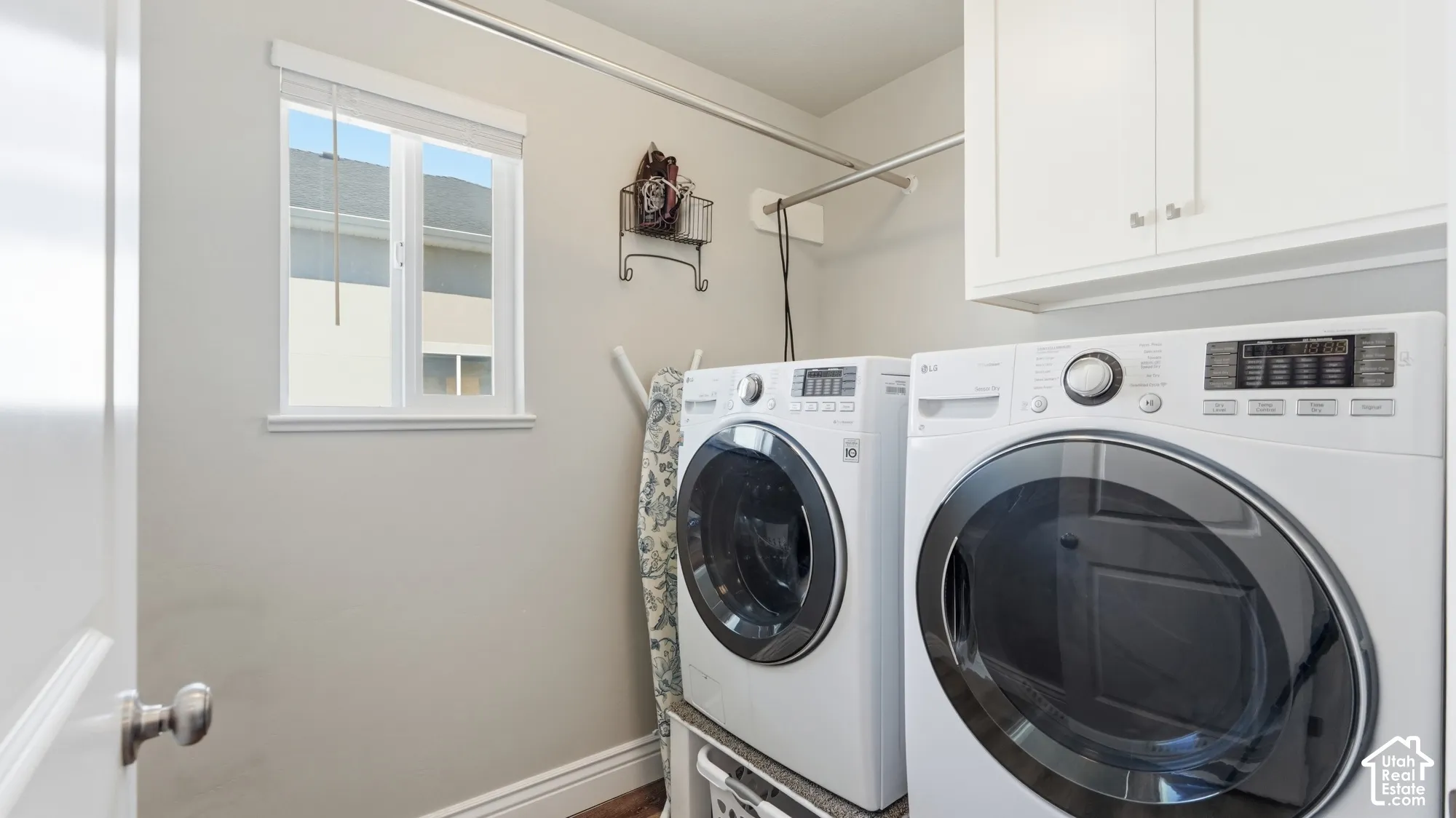 Laundry area featuring white cabinetry, a window, and a clothes hanging rod