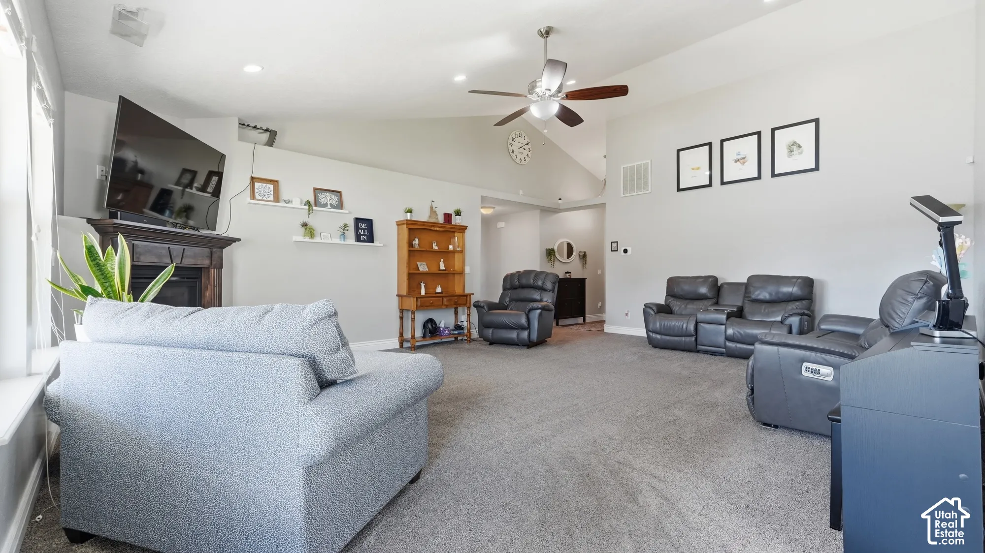 Vaulted ceilings, a built-in fireplace with a dark wood mantel, recessed lighting, and a ceiling fan