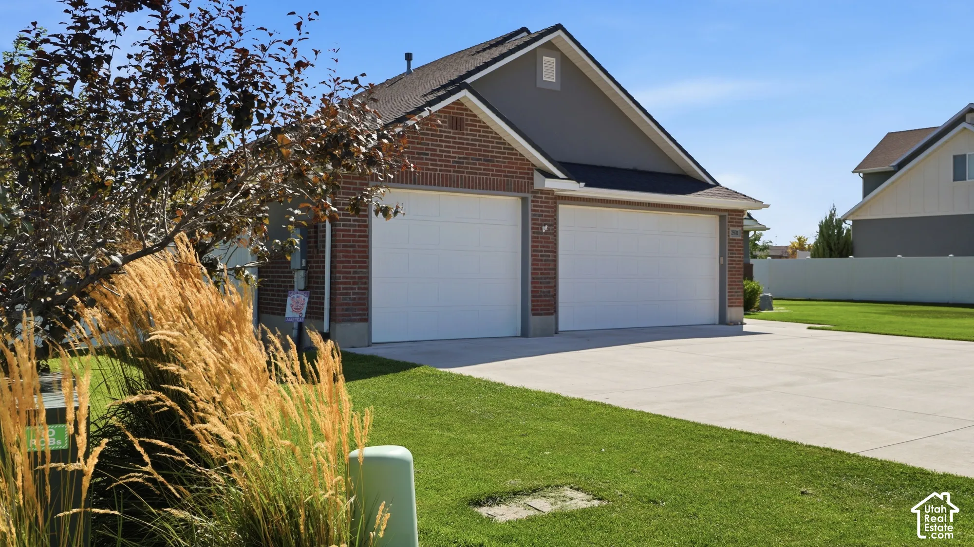 Brick and siding exterior with a two-car garage, concrete driveway, and manicured lawn