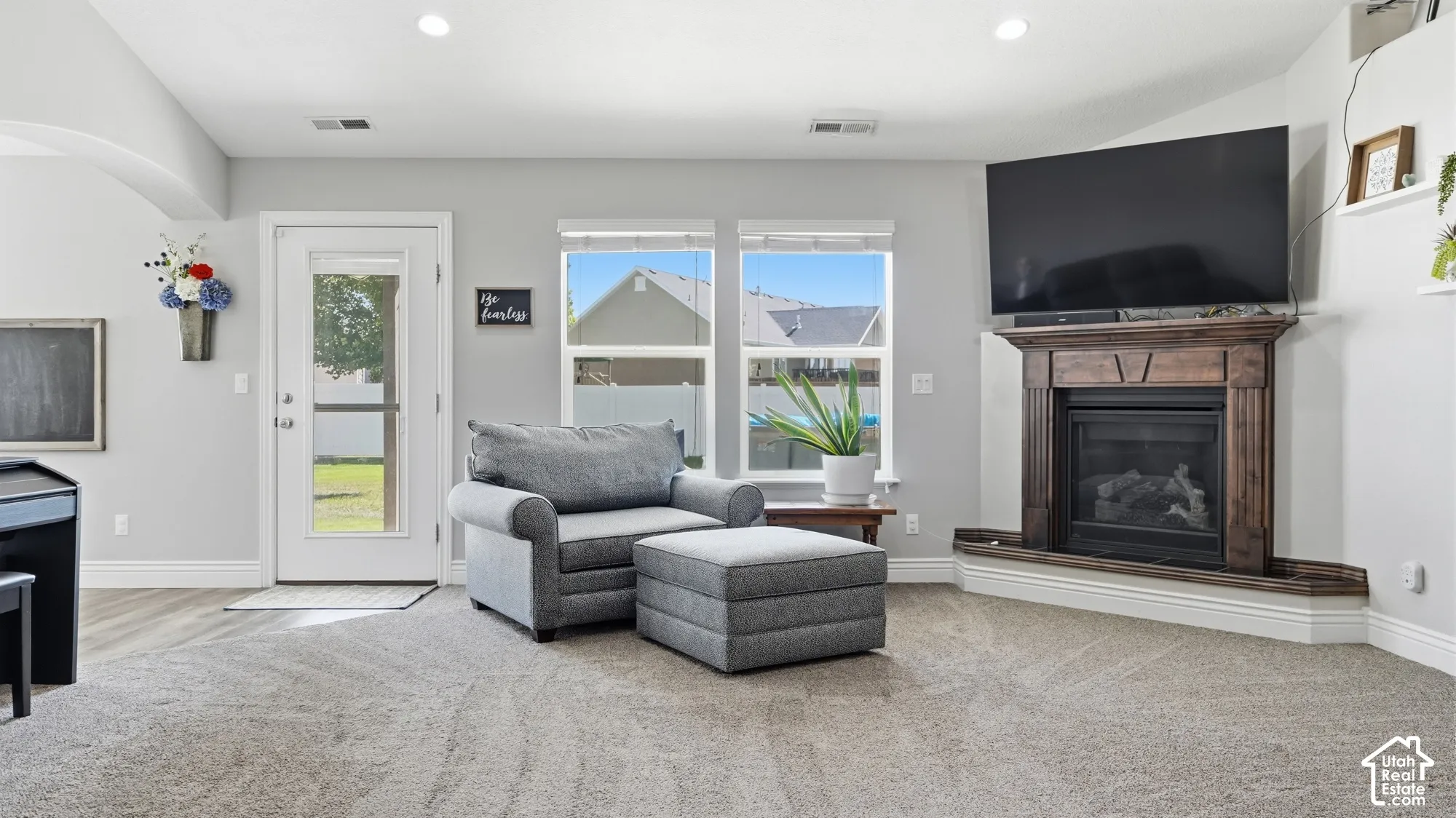 Living area featuring a corner-mounted fireplace with a wood-finish mantel, recessed lighting, and light-toned carpeting