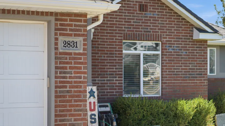 Brick exterior with white garage door, prominent house numbers, and a pitched roofline