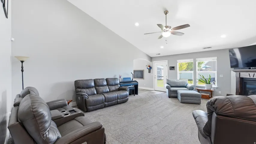 Vaulted ceiling, ceiling fan, recessed lighting, carpeted flooring, and a fireplace with a wood mantel