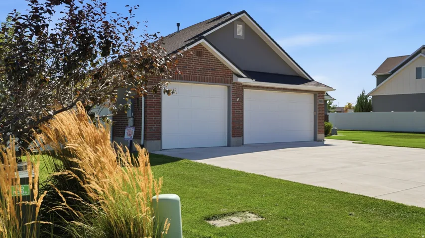 Brick and siding exterior with a two-car garage, concrete driveway, and manicured lawn