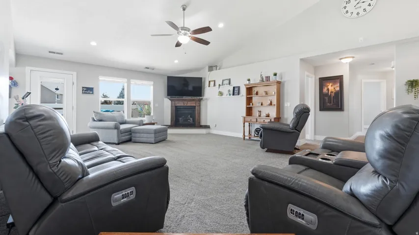 Vaulted ceilings with recessed lighting, ceiling fan, and a fireplace with a stone surround