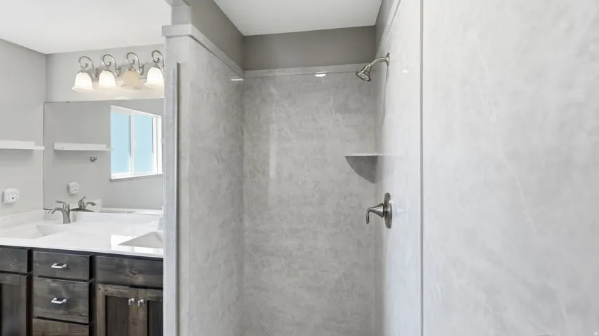 Walk-in shower with light-toned wall panels, built-in shelving, and a brushed nickel shower head