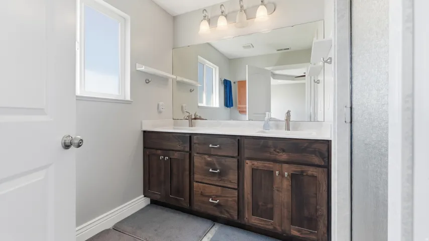 Dual sink vanity with dark wood-finish cabinetry, white countertops, and brushed nickel faucets