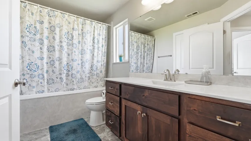 Wood-finish vanity with an integrated sink, polished chrome faucet, and spacious mirror