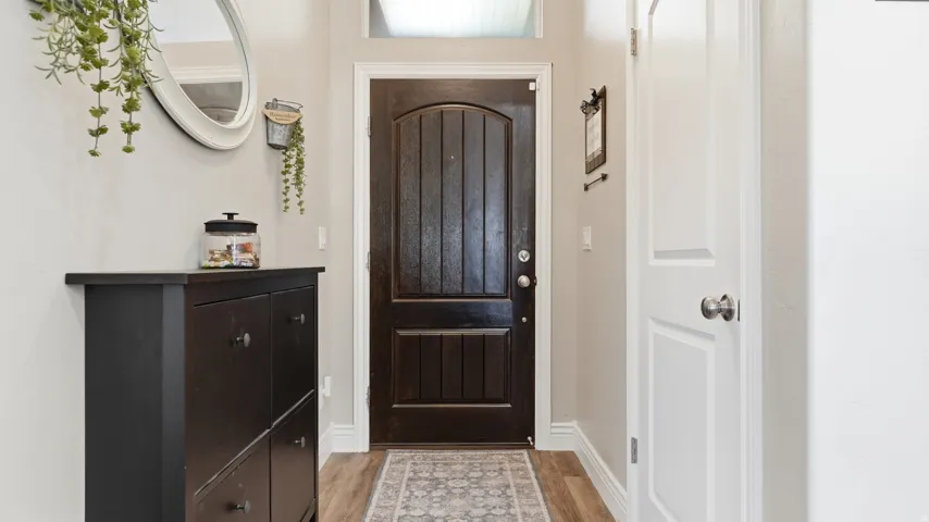 Arched panel front door, wood-finish flooring, and light wall paint